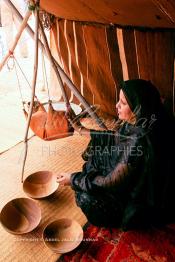 Image du Maroc Professionnelle de  Sous une tente bédouine une femme du Sahara prépare le petit lait de chamelle durant le grand Moussem de Tan Tan, classé en 2005 patrimoine immatériel humain mondial de l'Unesco. Le Moussem est une sorte de foire annuelle, à la fois économique, culturelle et sociale. chaque année la majorité des tribus et des grandes familles nomades du désert se retrouvent sur un site désertique "Place de la Tolérance et de la Paix " à la périphérie de Tan Tan où  danse, chants, course de chameaux et fantasia font partie des festivités. , Samedi 18 septembre 2004. (Photo / Abdeljalil Bounhar)